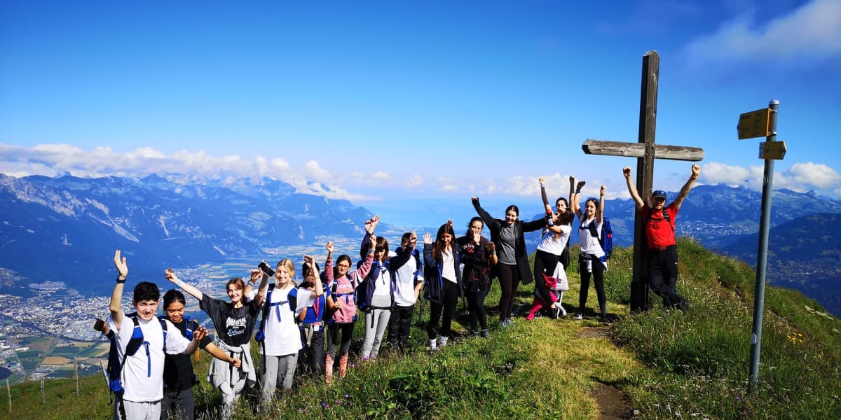 山の頂上で写真に写る子供たちと引率者