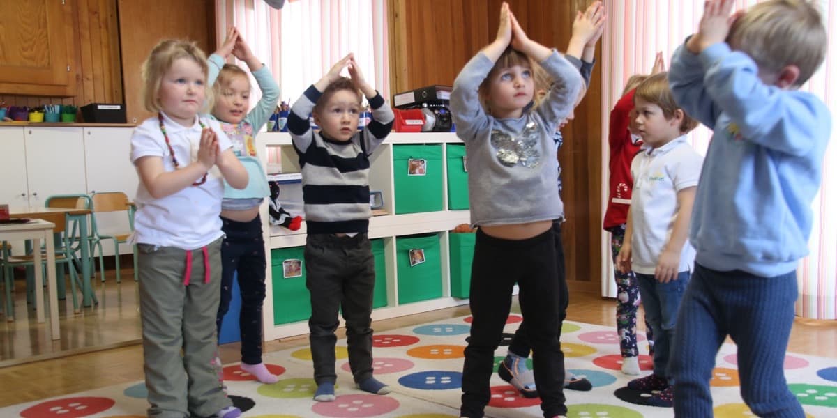 教室で手を合わせて体を動かす幼い子供たち