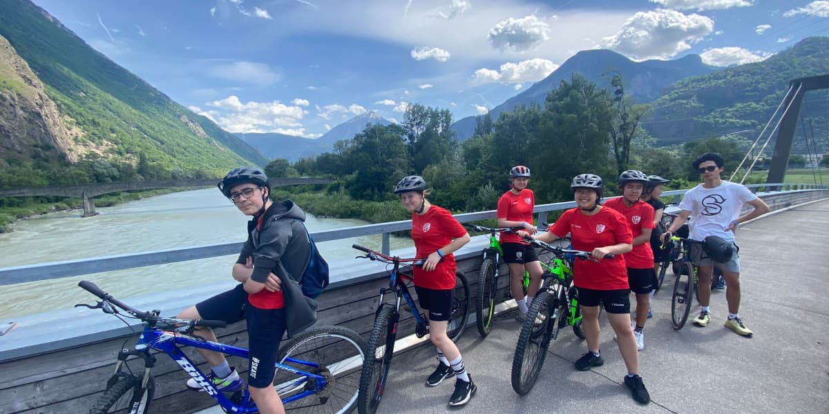 マウンテンバイクに乗り、橋の上で写真に写る子供たちと引率者
